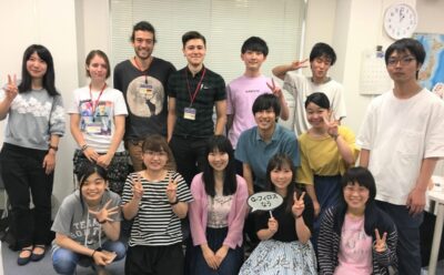 帰国前の留学生を囲んで集合写真
